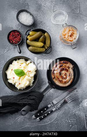 Traditional German Sausages with Mashed Potato and Sauerkraut in cast iron frying pan, on gray background, top view flat lay Stock Photo