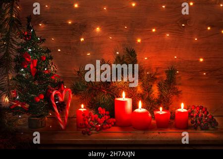 Christmas card with burning red candles, decorated with a Christmas tree, a heart made of striped candies and garland lights. Festive composition with Stock Photo