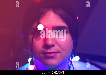 Christmas depression. Close-up crazy happy young woman celebrating christmas. Young people having fun on winter holiday time with colorful lights Stock Photo