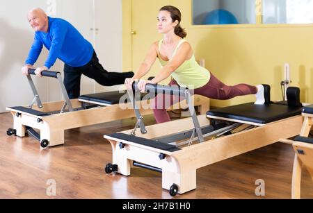 Woman and man doing exercises on Pilates reformer Stock Photo