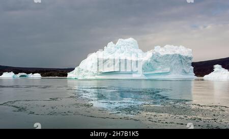 Blue iceberg reflected in sea ice, Rypefjord, Scoresby Sund, Greenland Stock Photo