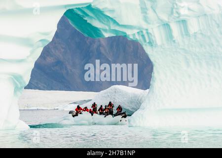 Photographers in zodiac shooting through an ice arch, Rypefjord, Scoresby Sund, Greenland Stock Photo