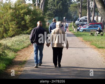 Elderly couple strolling hand in hand at Royal Victoria Country Park, Netley Abbey, Southampton, Hampshire, England, UK Stock Photo