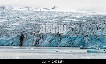 Glacial front of the Bredegletcher with bits of brash ice calved from its face, Vikingebugt Inlet, Scoresby Sund, Greenland Stock Photo