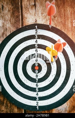 A game of darts is hanging on a vintage wooden wall. The concept of achieving goals and hobbies Stock Photo
