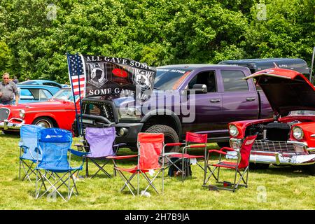Flags fly in front of a purple Dodge Ram pickup truck sitting between two classic cars at a car show in Fort Wayne, Indiana, USA. Stock Photo