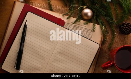 Open blank notebook with pen, coffee cup and Christmas tree on wooden table. Christmas concept. top view Stock Photo
