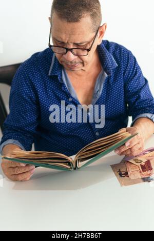 Latin man viewing photo album at home Stock Photo
