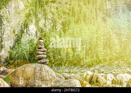 Balanced cairn on huge stone boulders on the banks of a mountain river. Zen pyramid. Stock Photo