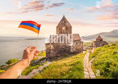 Armenian flag and famous Sevanavank Monastery on the shore of Lake Sevan. Travel landmarks and national patriotism concept Stock Photo