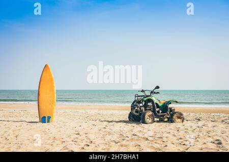 Vintage green ATV on the sandy beach. Quad ATV all terrain vehicle parked on beach, Motor bikes ready for action with summer sun flaring on bright day Stock Photo