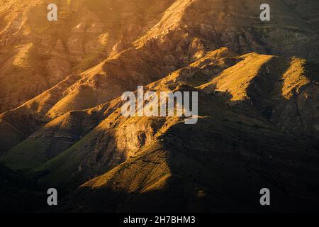 The folds of the mountains create an amazing pattern illuminated by the rays of the setting sun. The play of light and shadow Stock Photo