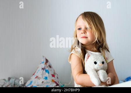 Portrait of a little girl in the children's room hugging a toy. Smiling in the background of the room. Stock Photo