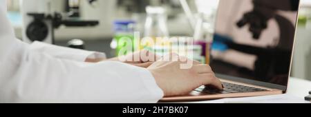 Scientist or student using laptop computer and microscope. online learning Stock Photo