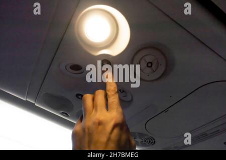 A finger pushing button, switching on the board top reading light in the economy class seat on Boeing 737-800 Stock Photo