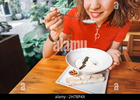 Woman eating traditional Armenian dish - spas soup made from fermented yogurt or matzoon. Two rolls of lavash on a plate Stock Photo