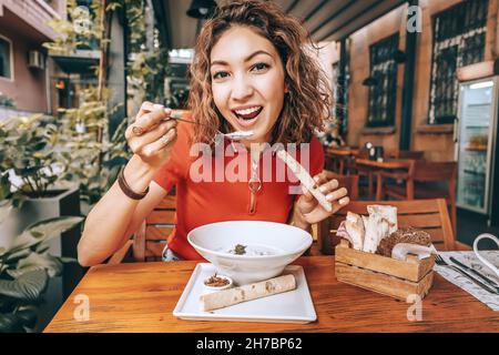 Happy cheerful woman eating lavash bread with traditional Armenian cuisine dish - spas soup made from fermented yogurt or matzoon. Stock Photo