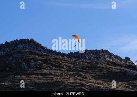 Paraglider flying over mountains in summer day in front of the mountain Stock Photo