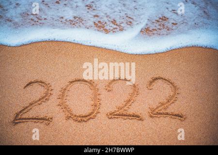 Happy New Year 2022 concept, lettering on the beach. Sea sunrise. Stock Photo