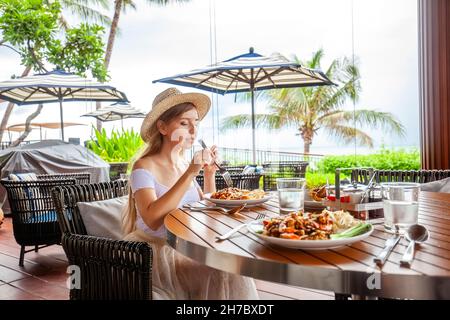 Happy young woman eating italian pasta in restaurant, female with food in cafe Stock Photo
