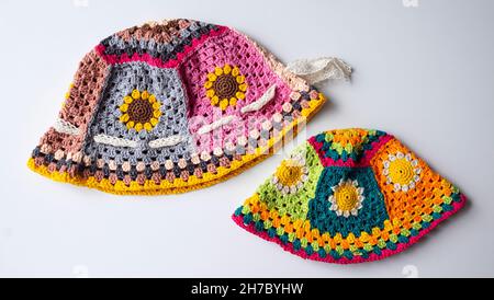 Top view handmade product to make spring present, colorful bucket hat with many piece link together, cute crochet hat from yarn on white background Stock Photo