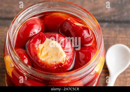 Stuffed cherry peppers with ricotta cheese filling in glass jar on wooden background Stock Photo