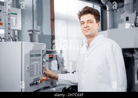 Male operator engineer controls production line from control panel, food factory. Stock Photo