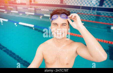 Portrait swimmer happy young man, background swimming pool blue water. Stock Photo