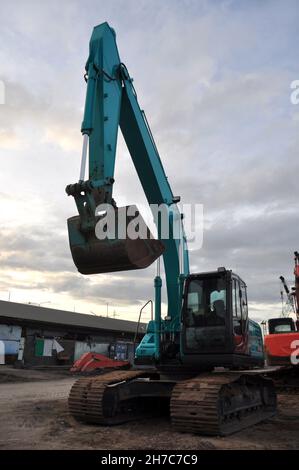 The green excavator vehicle after use and is parked by the port Stock Photo