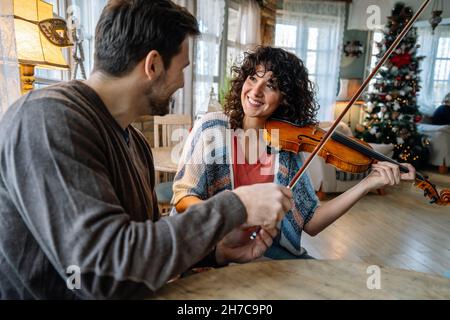 Private male music teacher giving violin lessons to a woman at home Stock Photo