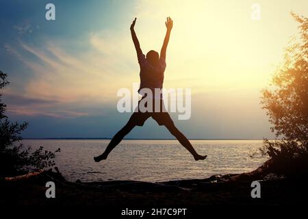 Toned Photo of Happy Person jumping on the Sunset Background Stock Photo