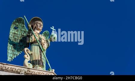 Saint Michael the Archangel defeats the Dragon, a medieval 13th century statue a the top of St Michael Church in Lucca (with copy space) Stock Photo