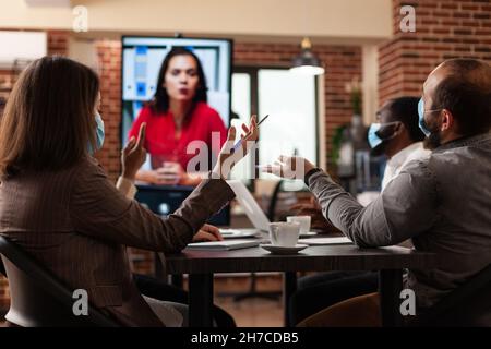 Entrepreneurs people explaining company strategy to remote collegue during online videocall meeting conference working in startup business office. Businessteam with medical face mask against covid19 Stock Photo