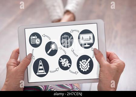 System maintenance concept shown on a tablet held by a woman Stock Photo