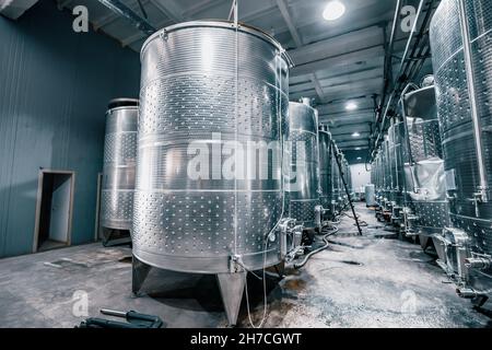 Large metal vats in which wine or beer is fermented at the factory at the winery. Concept of technologies and equipment for the production of alcoholi Stock Photo