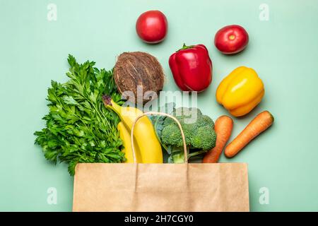 Eco friendly paper shop bag with raw organic green vegetables isolated on green background Flat lay, top view Zero waste, plastic free concept Stock Photo