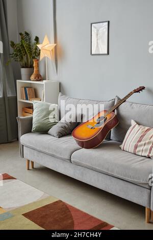 Vertical background image of cozy living room interior with acoustic guitar on blue sofa, copy space Stock Photo