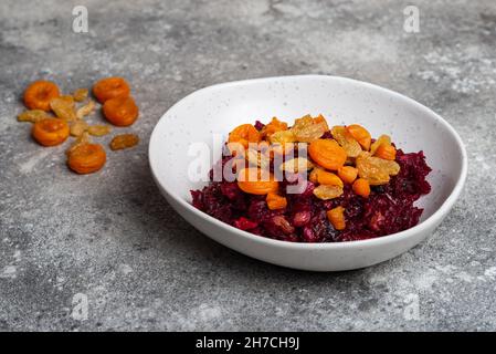 Beetroot salad with prunes in plate vegan food close-up on grey background Stock Photo