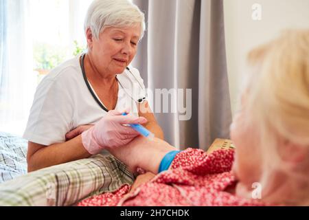 Doctor or nurse injects painkillers or vitamins into an elderly patient Stock Photo