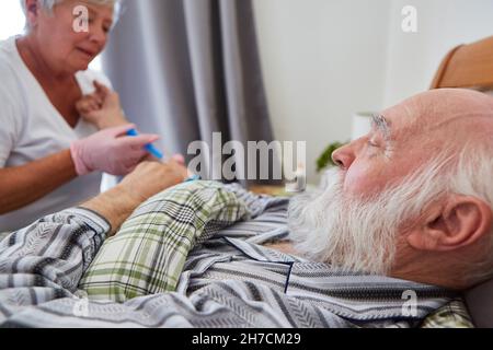 Nurse or doctor gives patient a syringe in the forearm in the nursing home Stock Photo