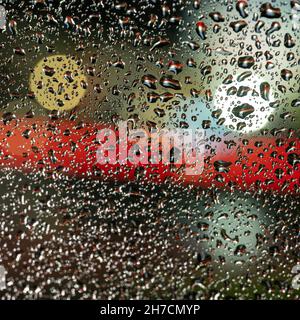 colorful diffuse unsharp lights behind glass window with rain drops Stock Photo