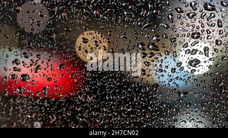 colorful diffuse unsharp lights behind glass window with rain drops Stock Photo