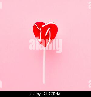 Red lollipop heart on a white stick over pink background. Top view, copy space for text Stock Photo