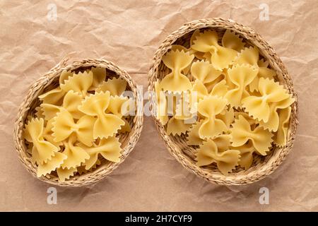 Light yellow butterfly paste in a straw plates on brown paper, close-up, top view. Stock Photo