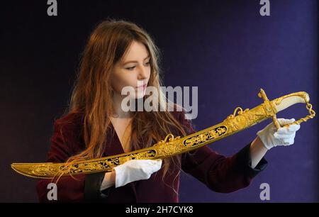 A Bonhams employee displays the Lloyd's Patriotic Fund Trafalgar Sword awarded to Philip Durham, Captain of HMS Defiance at the Battle of Trafalgar, one of the items for sale in Bonhams' forthcoming Antique Arms and Armour sale on November 24th in London. Picture date: Monday November 22, 2021. Stock Photo