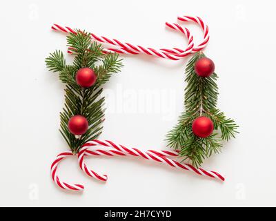 Christmas blank frame, candy canes and Xmas tree twig isolated on white background. Fresh fir and decoration border, space. Holiday greeting card desi Stock Photo