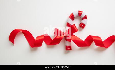 Candy cane with red ribbon bow isolated on white background. Christmas peppermint red white dessert. Merry Xmas greeting card template, copy space Stock Photo