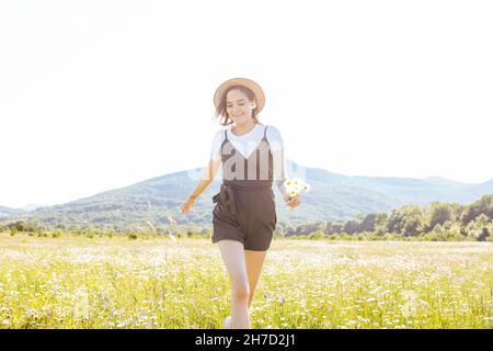 a beautiful woman in a dress running around the field with daisies Stock Photo