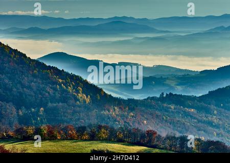 Foggy autumn landscape with mountain , the sun breaking through the clouds. Valley with mixed forest and colorful trees. View Vrsatec hill, Slovakia. Stock Photo