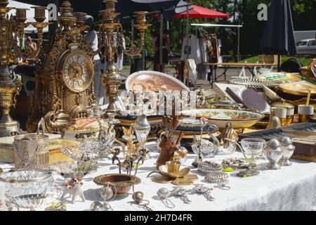 Different antiques on flea market or traditional festival - vintage silver and ceramic dishes, old clock, candlesticks and other vintage things Stock Photo